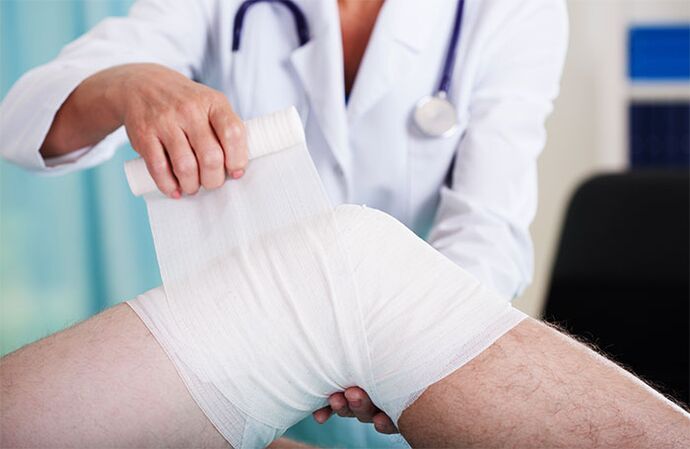 Doctor bandaging knee joint